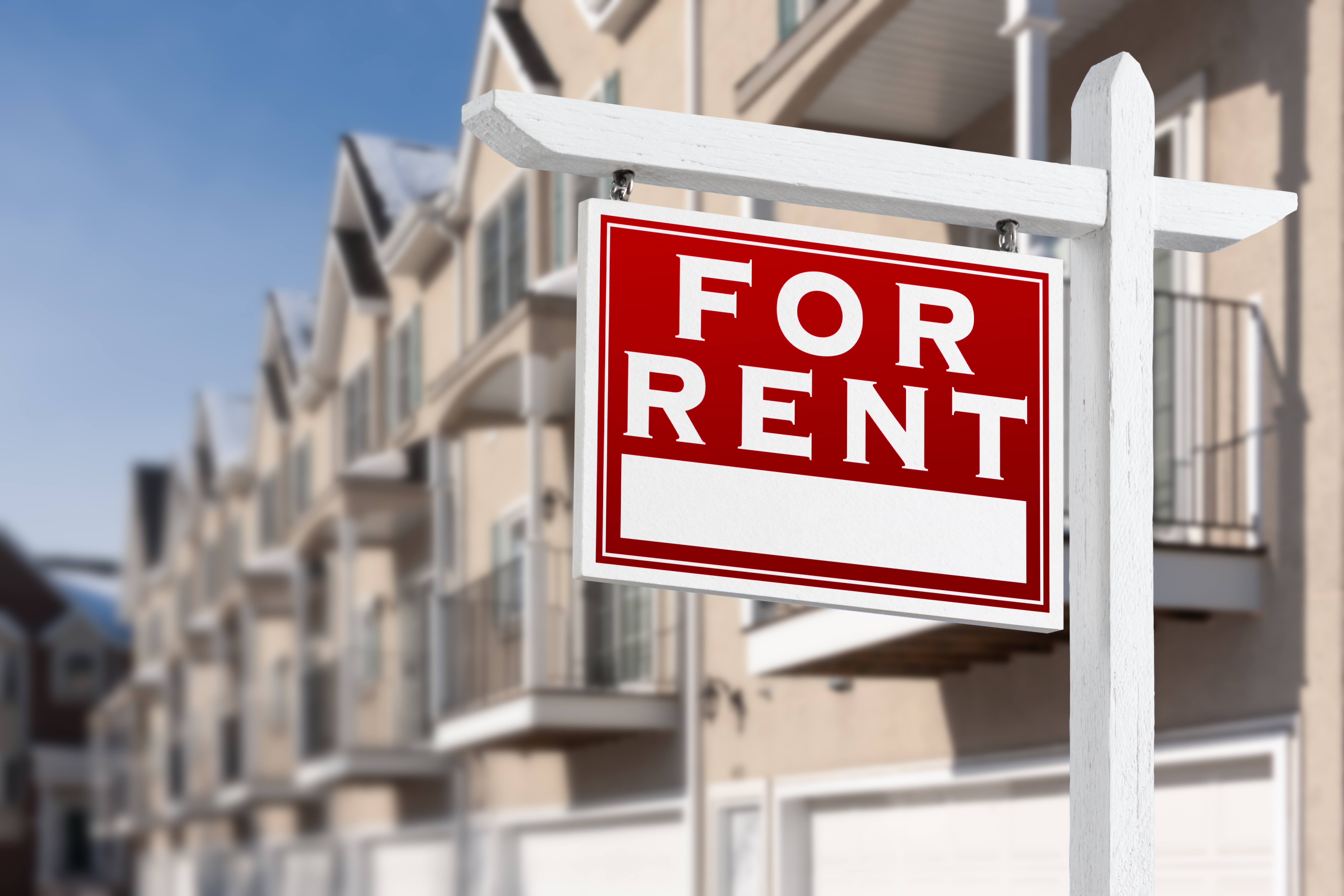 A red "For Rent" sign outside an apartment building