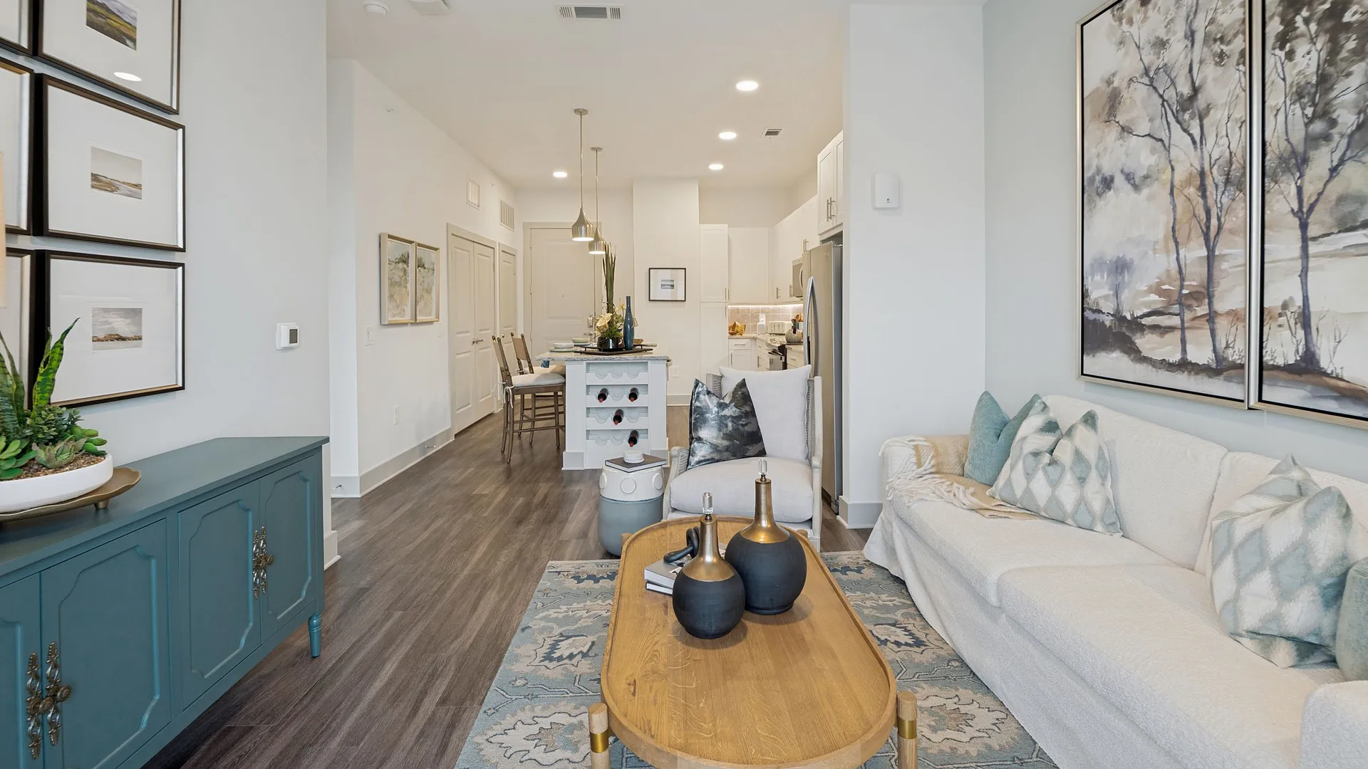 A modern living room with a cozy sofa, stylish decor, and an open kitchen area.