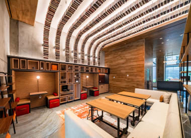 a large living room with tables and a kitchen in a lobby