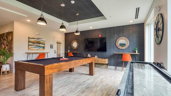 A room with a pool table and a television.