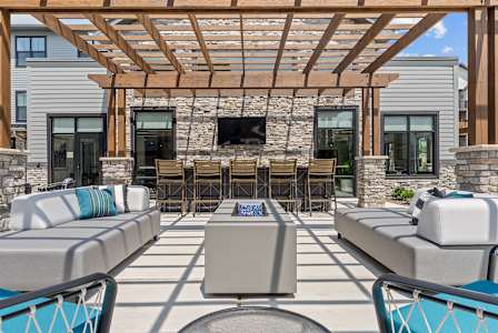 A patio with a stone wall and a wooden pergola.