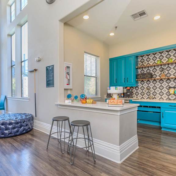 a kitchen with blue cabinets and a counter with three stools