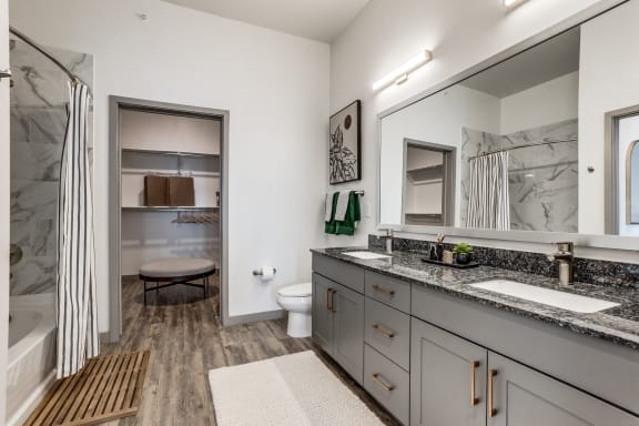a bathroom with gray cabinets and a shower and a sink and a toilet