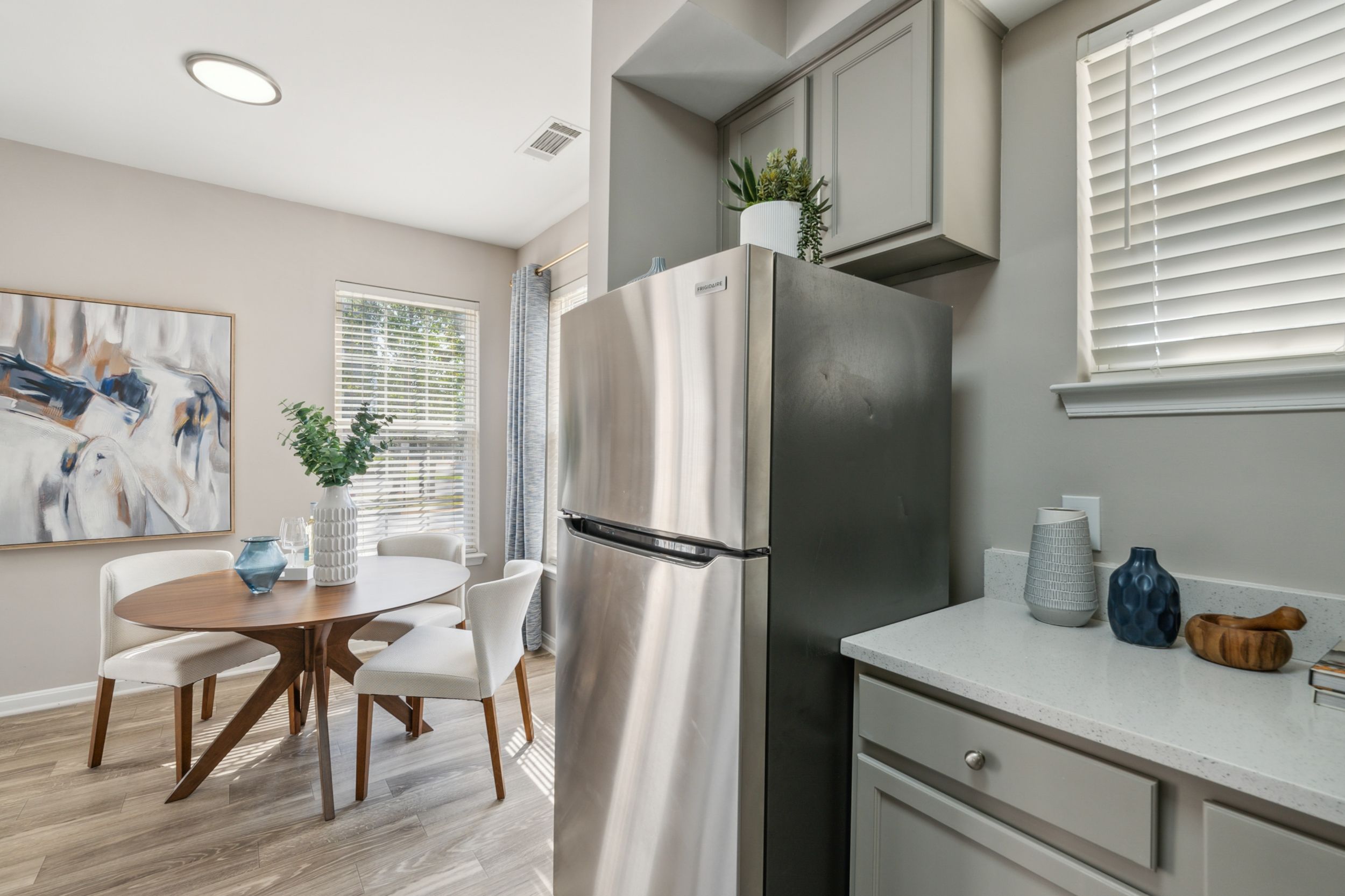 A modern kitchen with stainless steel appliances and a dining area featuring a round table and chairs.