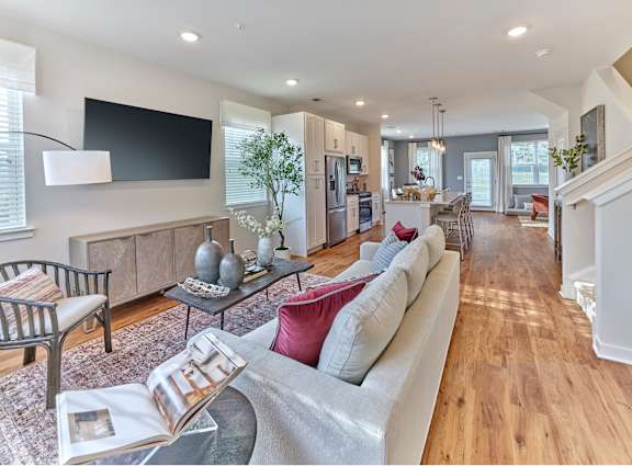 A modern living room with a grey sofa, a coffee table, and a television on the wall.