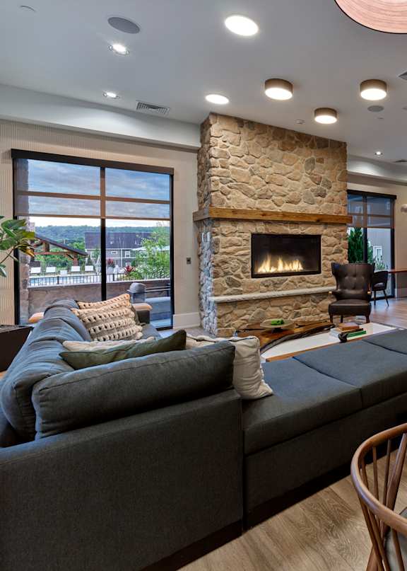 A modern living room with a stone fireplace and a large grey sofa.