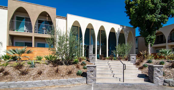 A building with arched windows and a stone staircase leading to the entrance at Veranda La Mesa in La Mesa, 91942