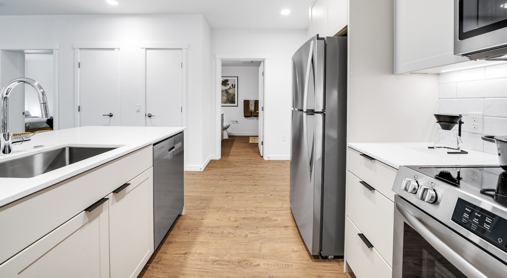1, 2, & 3 Bedroom Apartments in Yesler Terrace, Seattle, WA - Swell - A Kitchen with Stainless Steel Appliances, White Countertops, and Wood Style Flooring