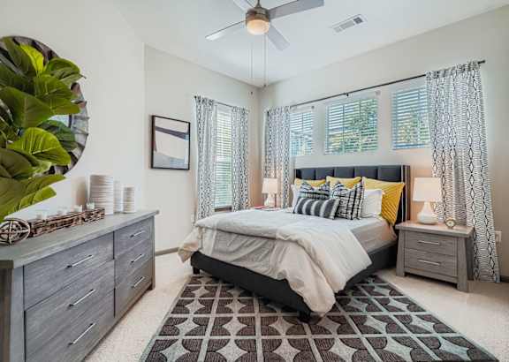 A bedroom with a bed, nightstand, and a plant.