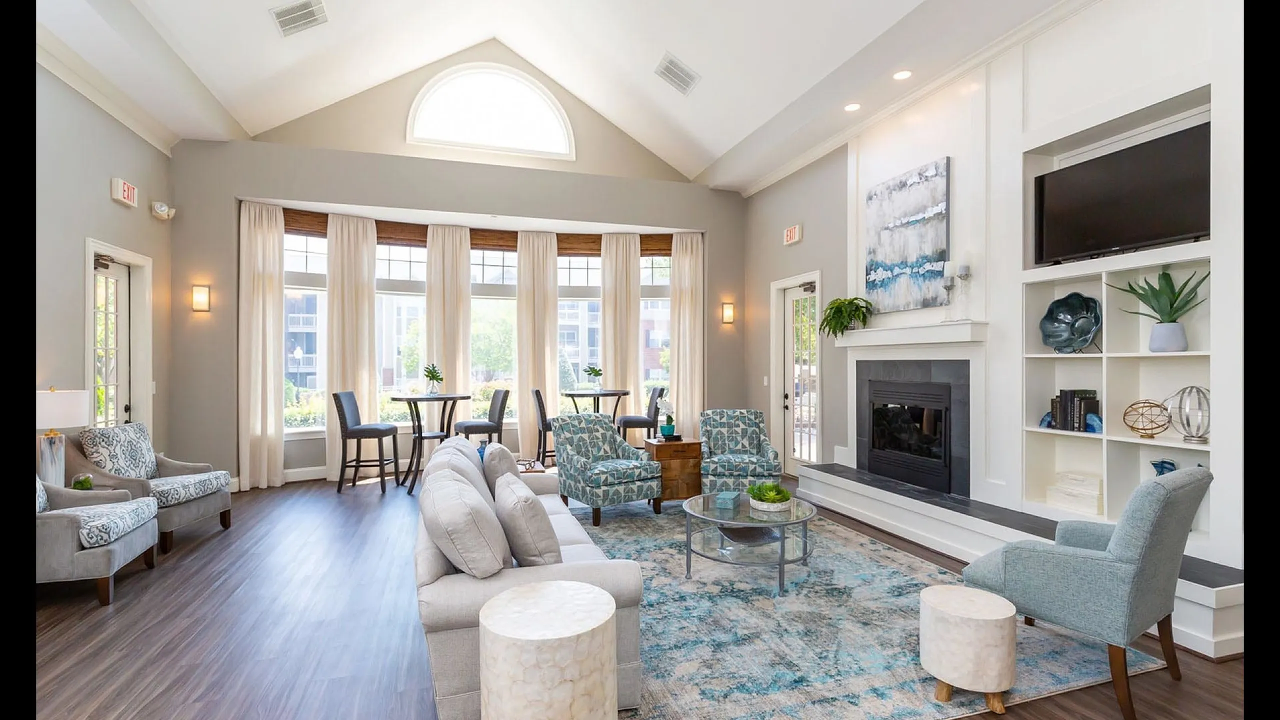 Bright and inviting living room with vaulted ceiling and fireplace, featuring elegant seating and large windows for natural light.