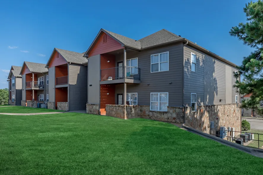 a two-story apartment building surrounded by luscious green grass