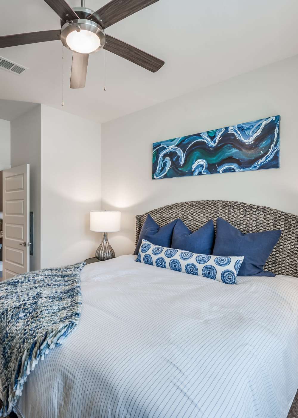 Modern vibrant bedroom with side lamp and ceiling fan at Tate Tanglewood in Houston, Texas