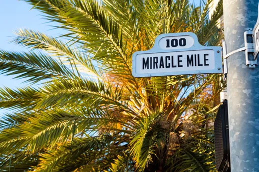 Miracle Mile street sign in front of palm tree.
