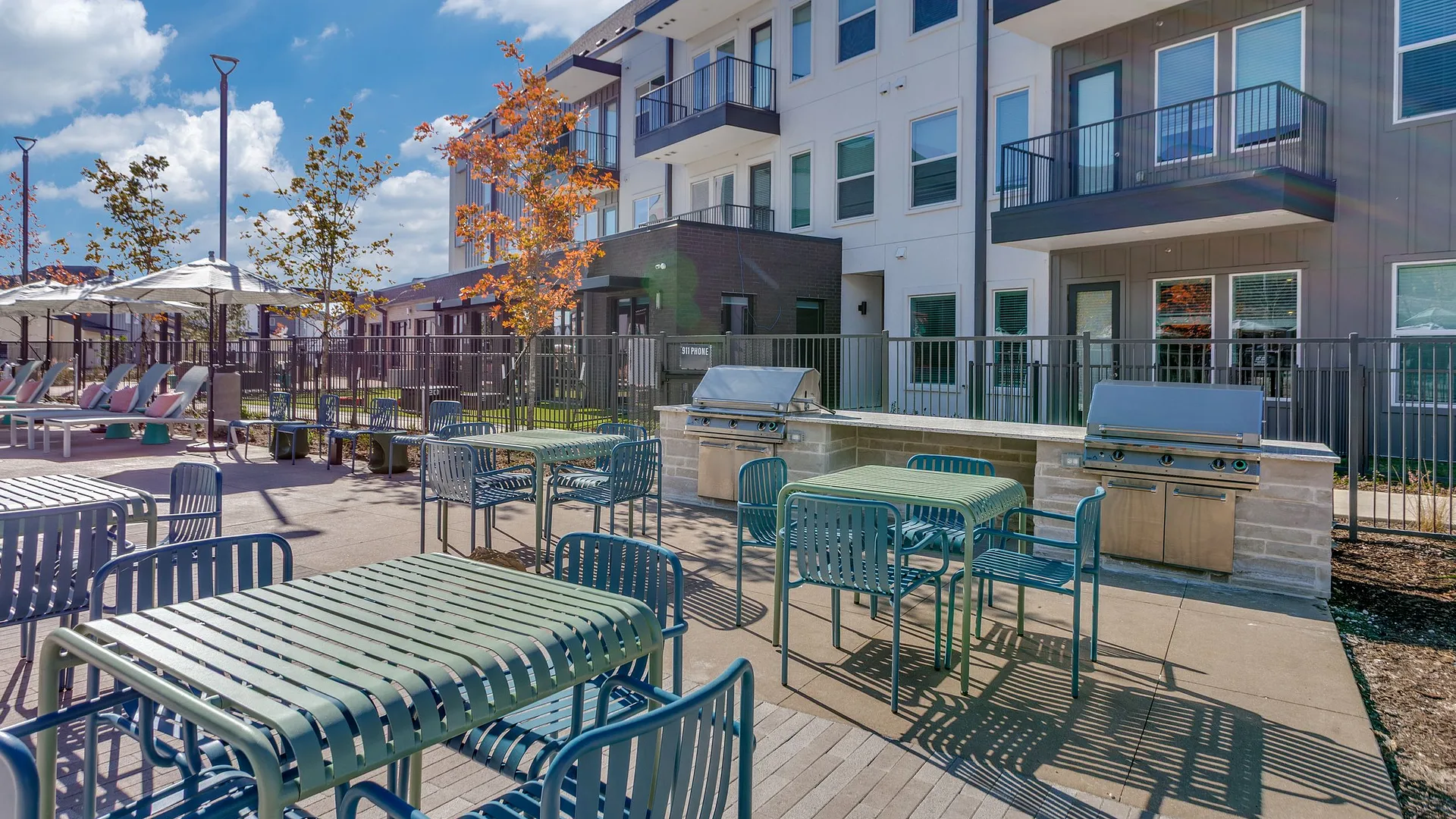 Outdoor grilling area with seating next to a modern apartment complex.