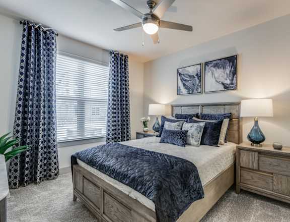 A bedroom with a bed, nightstand, and a ceiling fan.