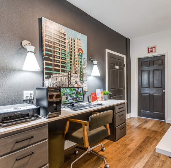 a desk with a computer and a printer in a room with a door that is open