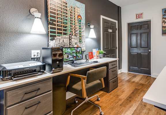 a desk with a computer and a printer in a room with a door that is open