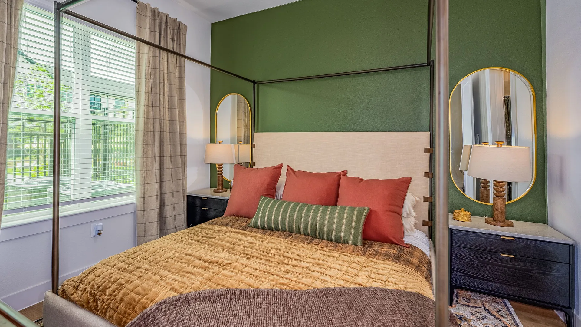 A stylish bedroom featuring a green accent wall, a cozy bed with pillows, and elegant decor.