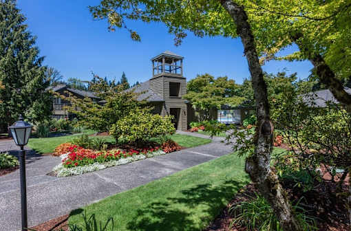 A house with a tower-like structure on the roof is surrounded by a well-manicured garden.