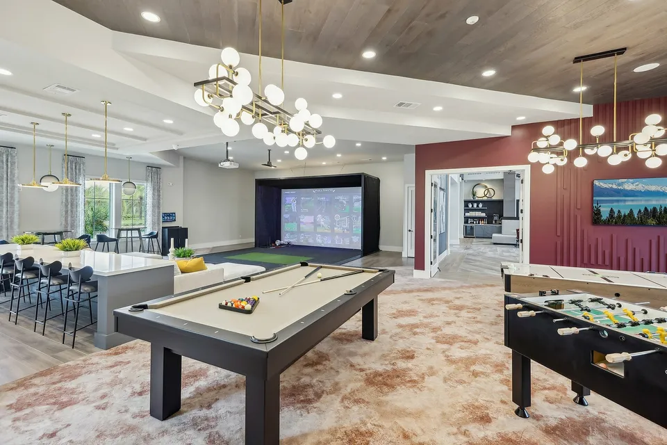 Luxurious game room showcasing modern decor with a pool table, foosball, and virtual golf setup under stylish lighting.