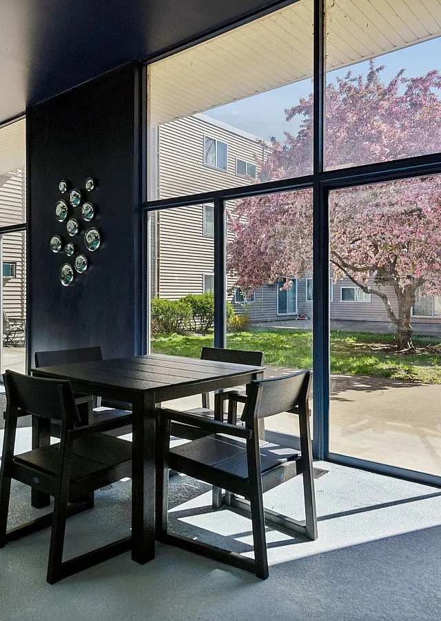 Charming interior with modern seating and large glass windows showcasing a vibrant blossom tree courtyard.