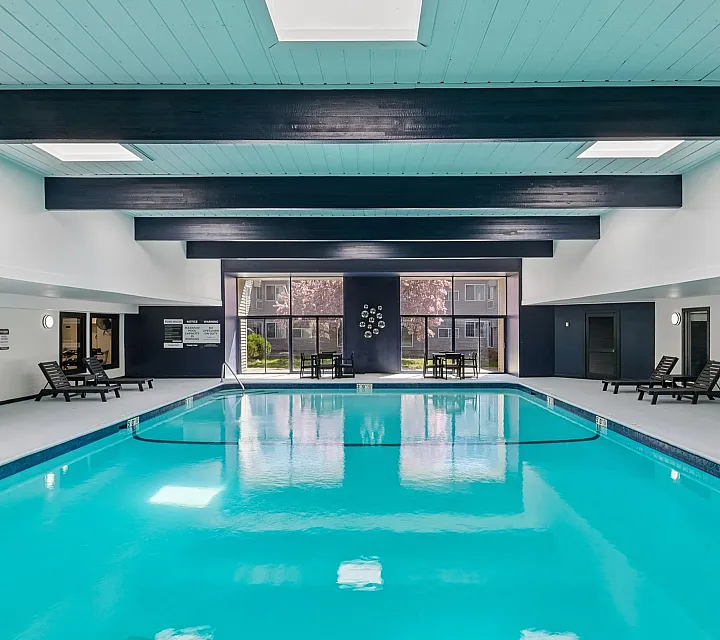 Luxurious indoor swimming pool area with modern skylights and sleek lounge chairs, perfect for relaxation and leisure.