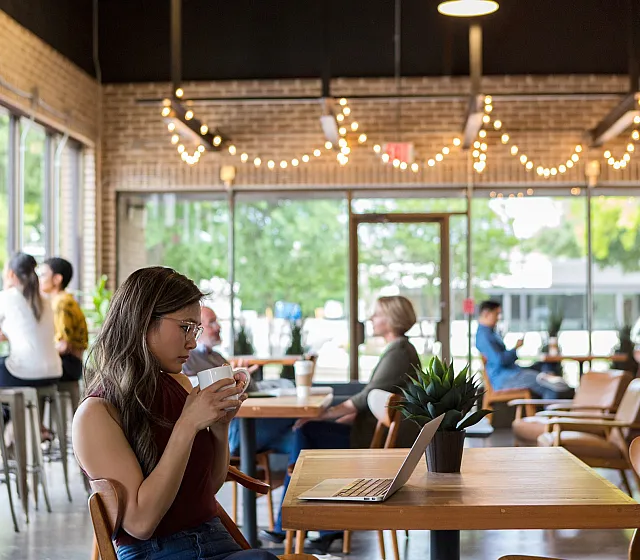 Inviting cafe near ReNew Minnehaha with cozy secasating, warm lighting, and large windows showing a lush green view, perfect for working or relaxing with a coffee.