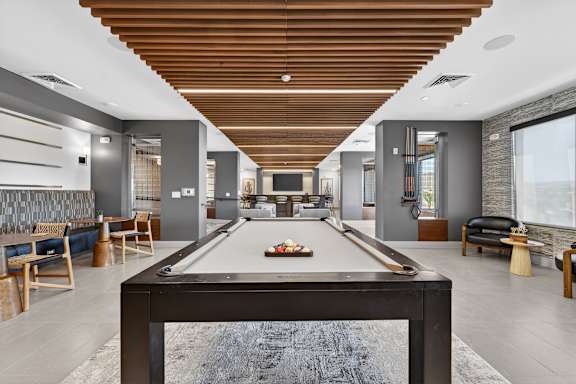 A pool table is in the middle of a room with a wooden ceiling.