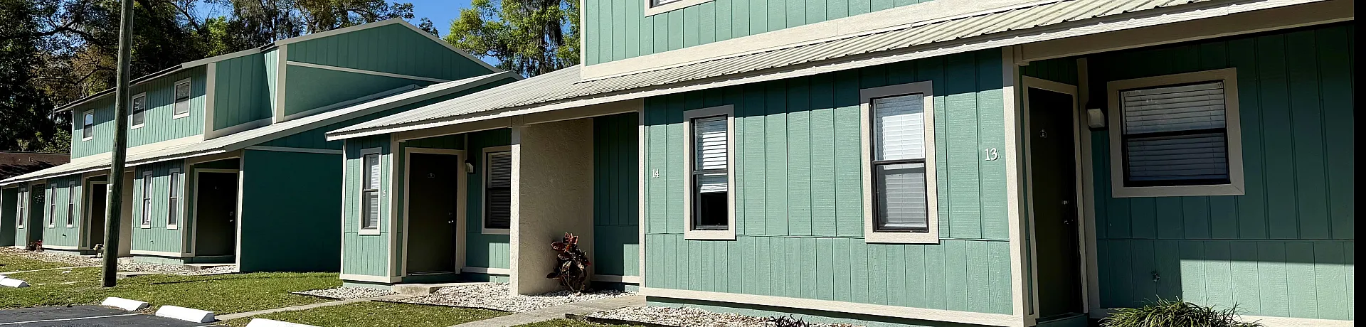 Charming green townhouses with modern architecture nestled in a serene neighborhood surrounded by lush greenery.