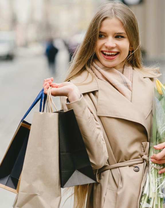 woman holding shopping bags and a bunch of flowers