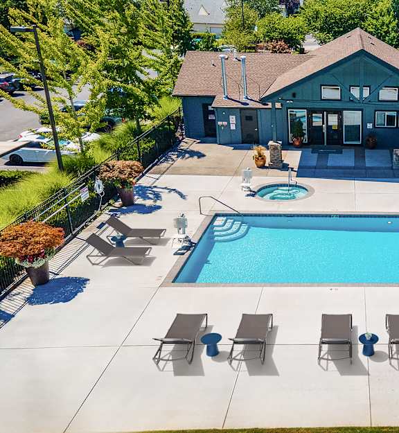 A pool with lounge chairs and a building in the background.