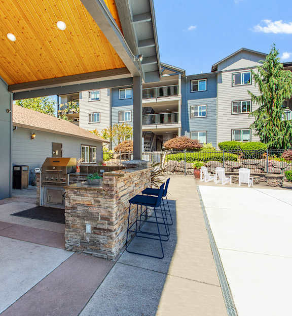 A patio area with a stone wall and a wooden roof.