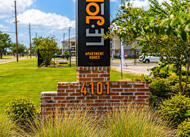 A sign for Le Joliet apartment homes stands in front of a brick wall.