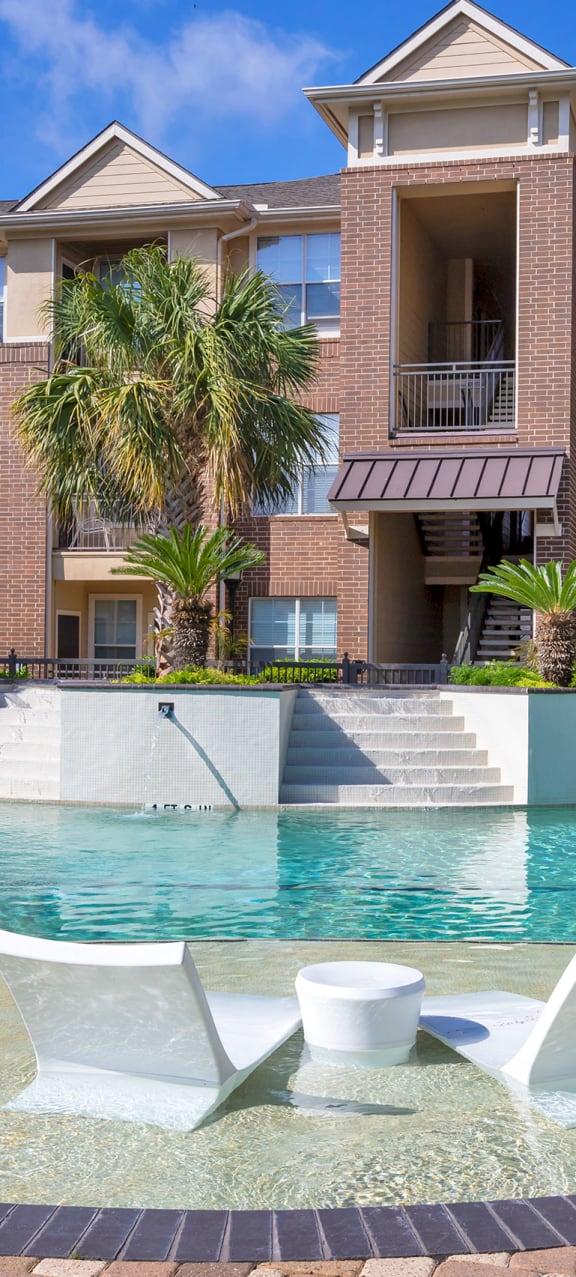 a swimming pool with chairs and a house in the background at Madison on the Meadow in Texas 77477