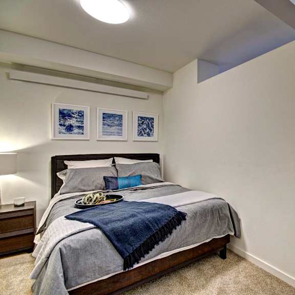 A bedroom with a bed, nightstand, and two pictures on the wall.
