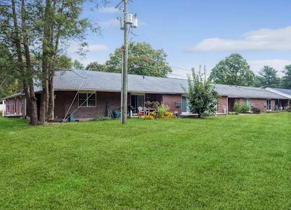 a view of the front of a brick house with a green yard