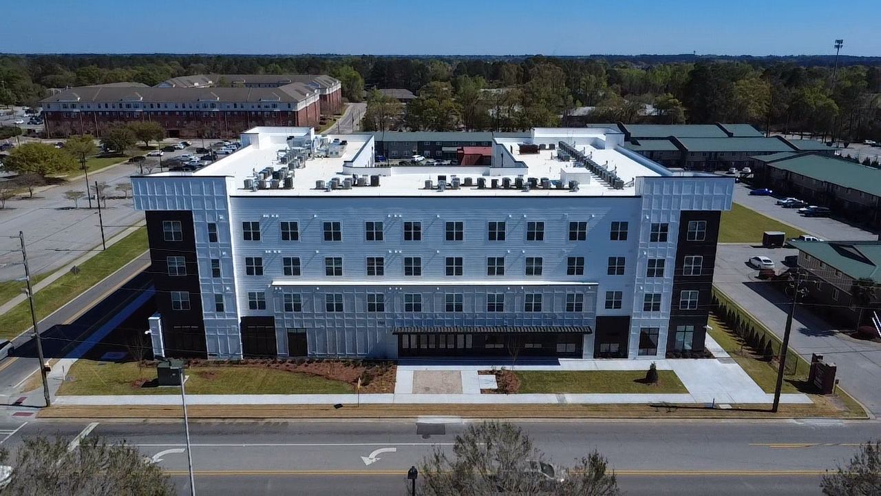 Aerial view of a white, multi-building apartment complex with parking around it.