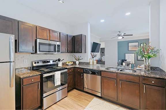 A kitchen with dark wood cabinets and stainless steel appliances at Pecan Springs, San Antonio, TX