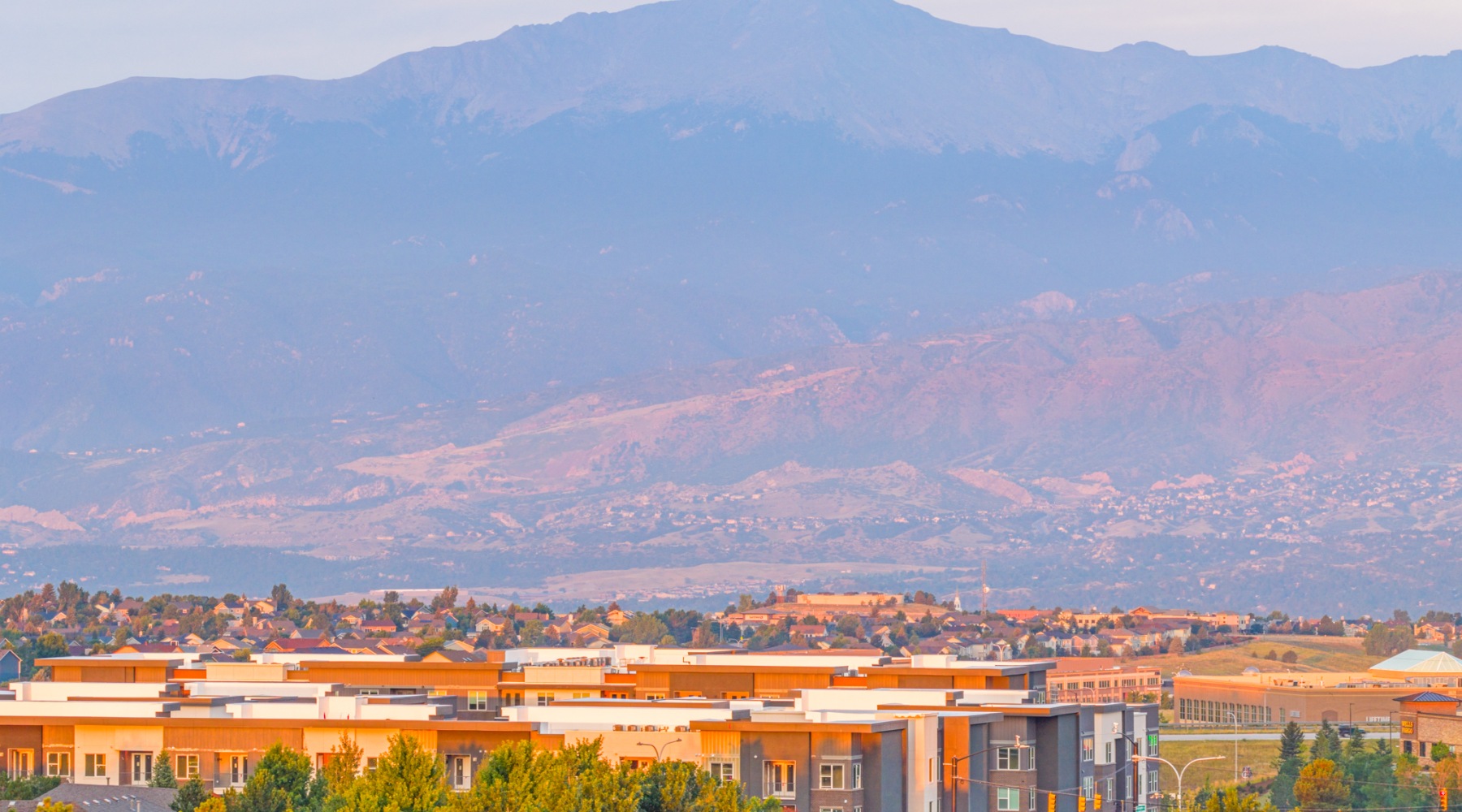 Scenic apartment complex with breathtaking mountain views, surrounded by lush greenery and vibrant community living at The Aven in Colorado Springs
