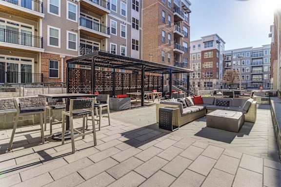 a large patio with tables and chairs in front of a building at Dartmoor Place at Oxford Square Apartments, Maryland, 21076
