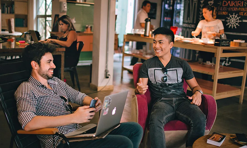 two men working on laptops at a coffee shop