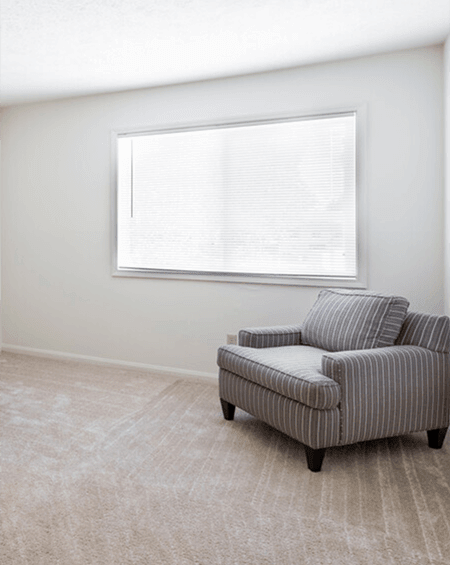 A striped armchair sits in a room with a window.