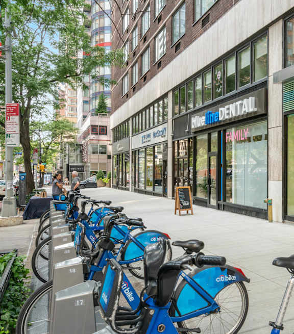 A street view with people walking on the sidewalk and a building with a sign that says "5th Ave Station".
