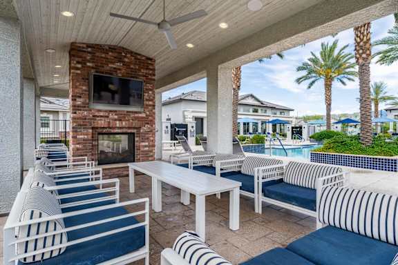 A patio with white furniture and a brick fireplace. at Vistoria At Stadium Apartments, Glendale, Arizona