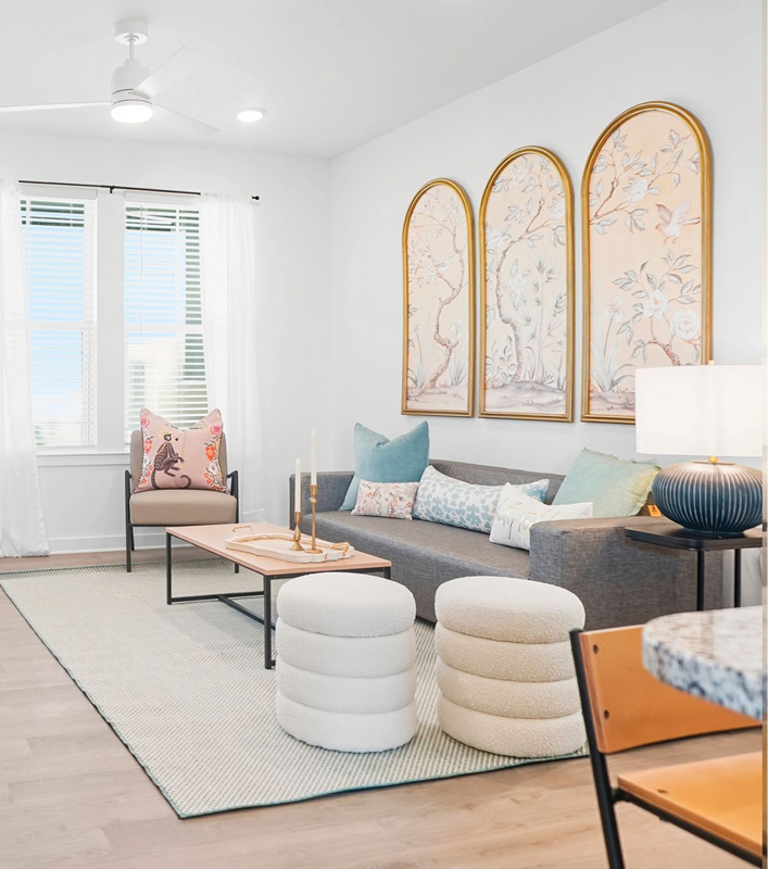 Modern living room with gray sofa, decorative pillows, wall art, and stylish furniture in bright natural light.