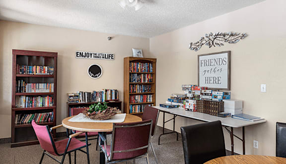 A room with a table, chairs, and bookshelves.