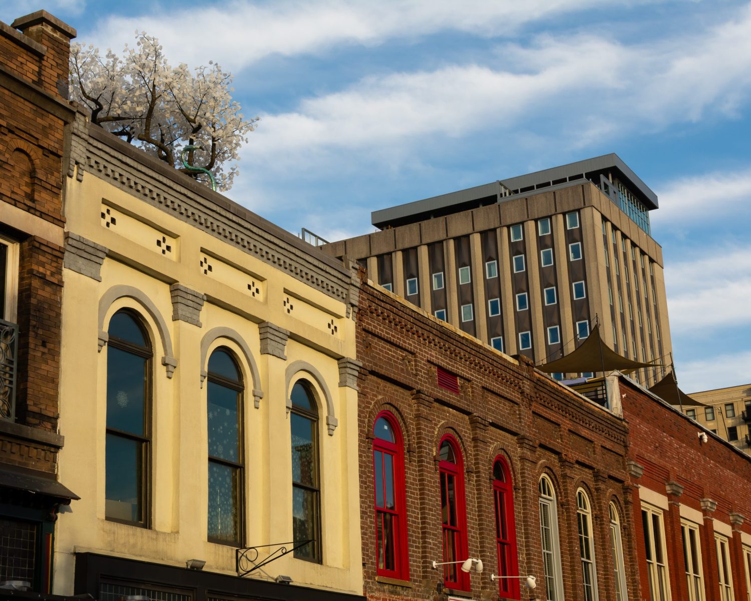 Apartments For Rent Downtown Knoxville Row of colorful urban buildings with diverse architectural styles under a blue sky with clouds. Knoxville Apartments