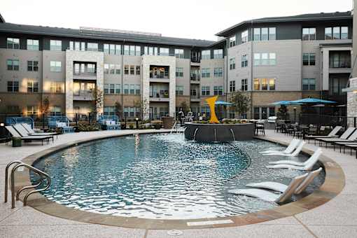 A round swimming pool with a waterfall in the middle of it.