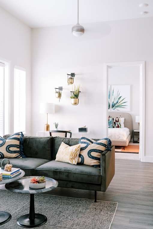 A living room with a grey couch and a glass table.