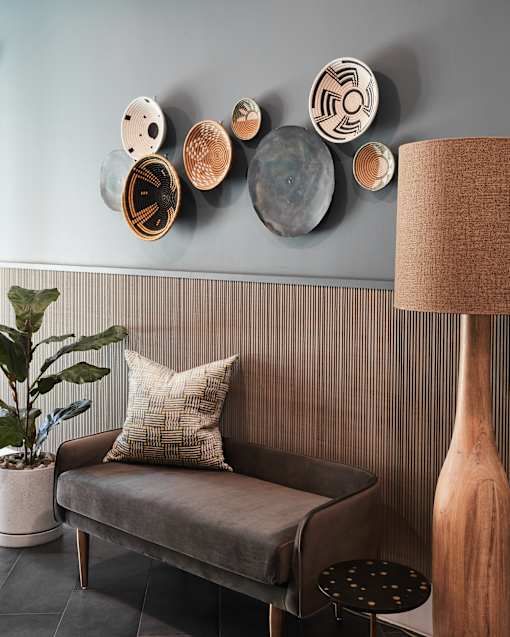 A grey couch with a pillow and a plant on the side.